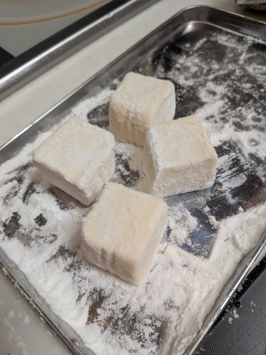 Tofu pieces coated in potato starch on a baking tray