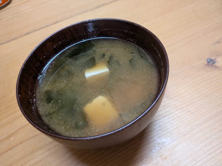 Finished miso soup in a dark Japanese bowl with tofu, wakame and green onions