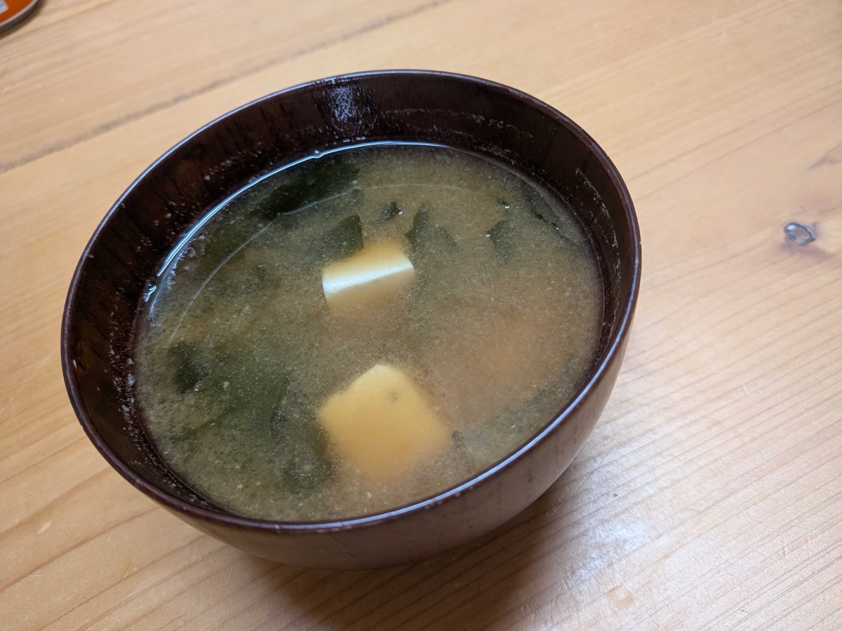 Finished miso soup in a dark Japanese bowl with tofu, wakame and green onions