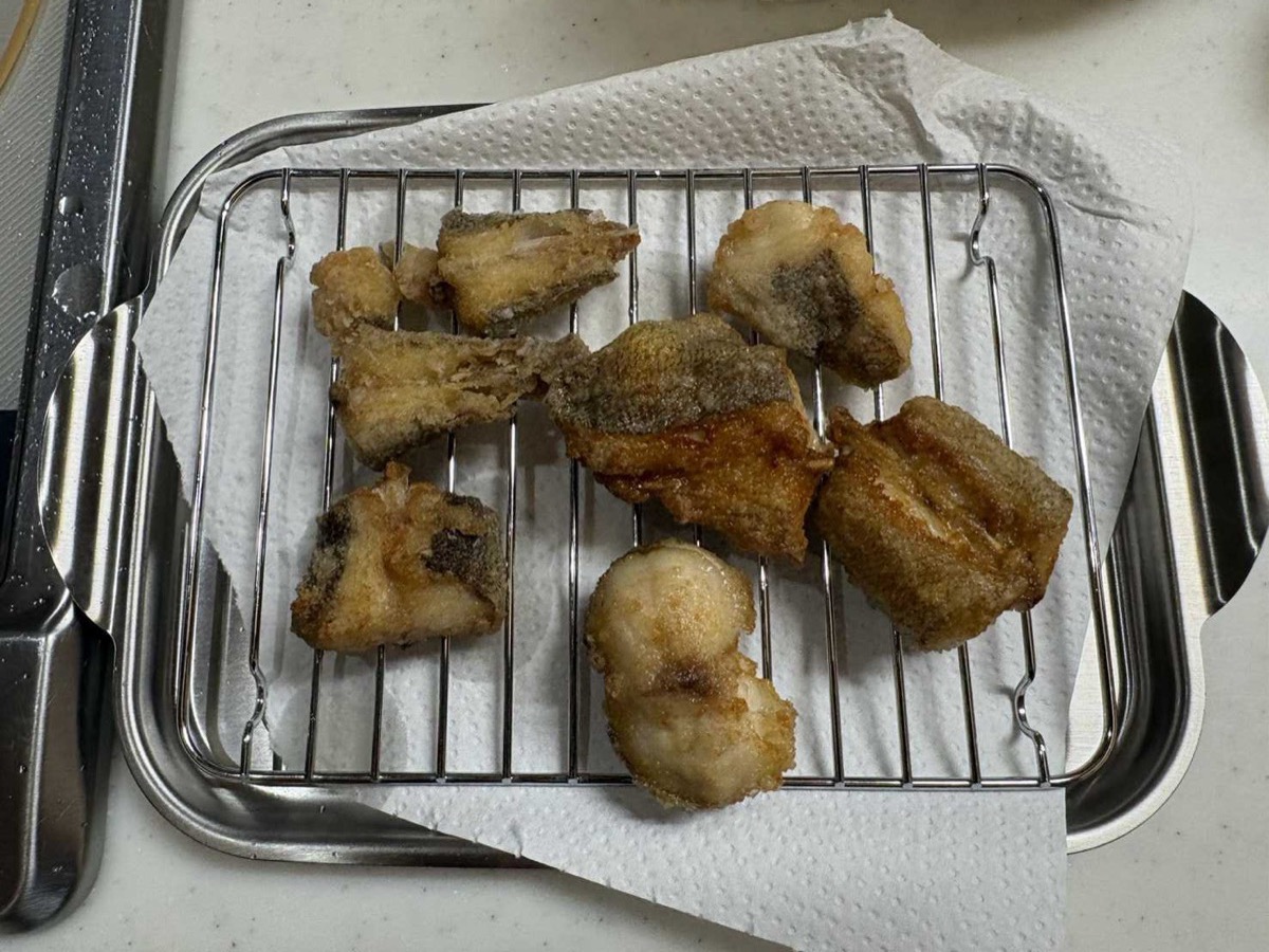 Fried kochi fish pieces draining on a wire rack