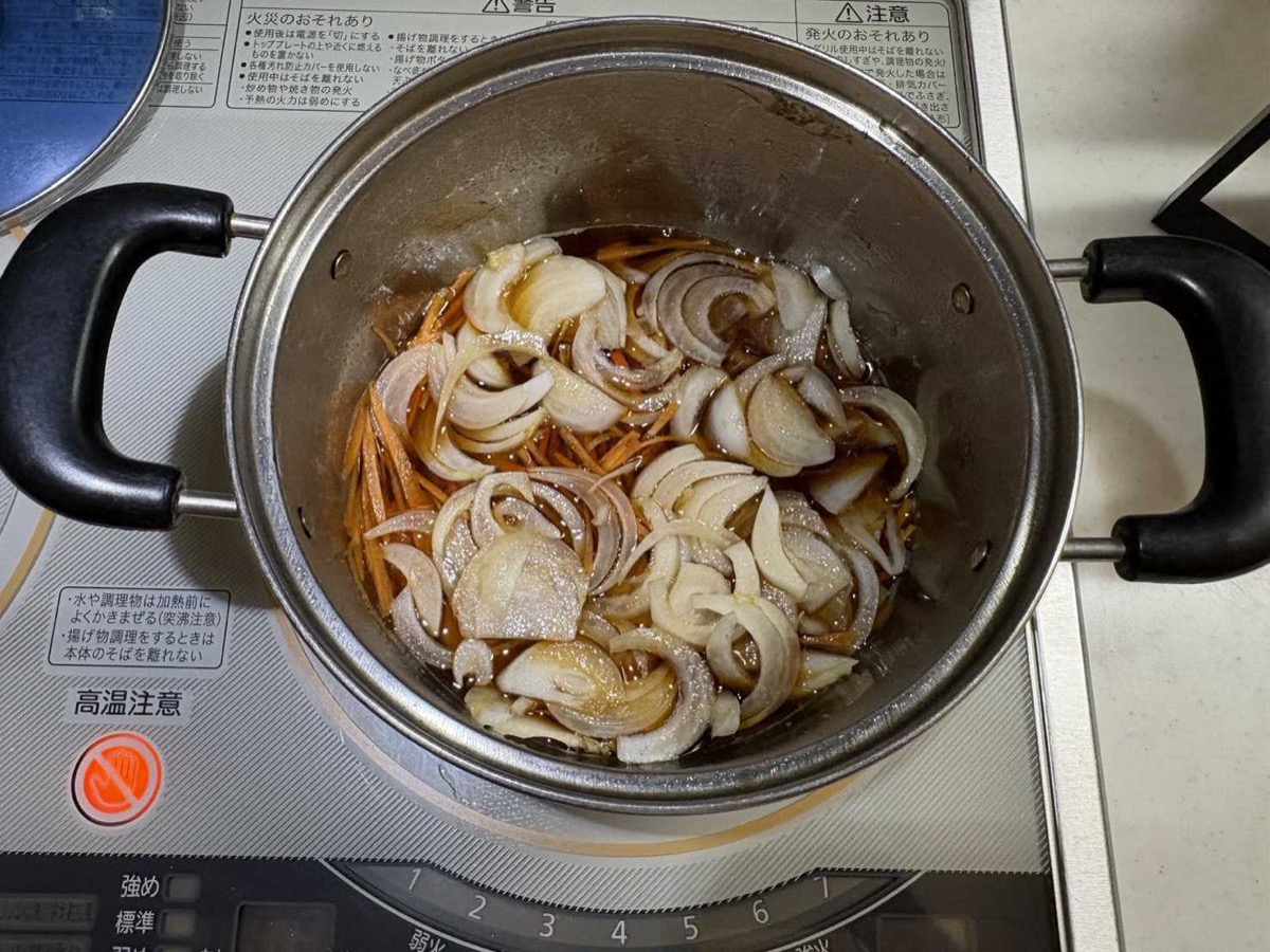 Sliced onion and carrot cooking in nanban sauce in a pot