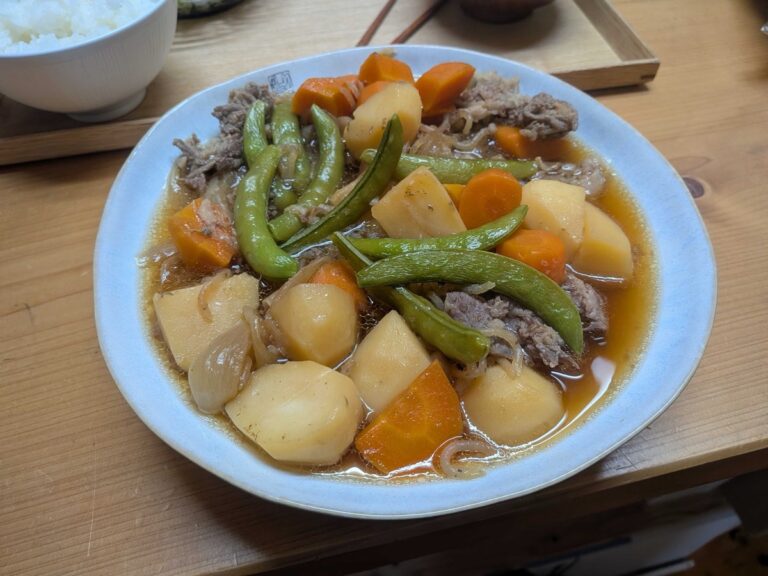 Nikujaga Japanese meat and potatoes served on a plate with snap peas on top
