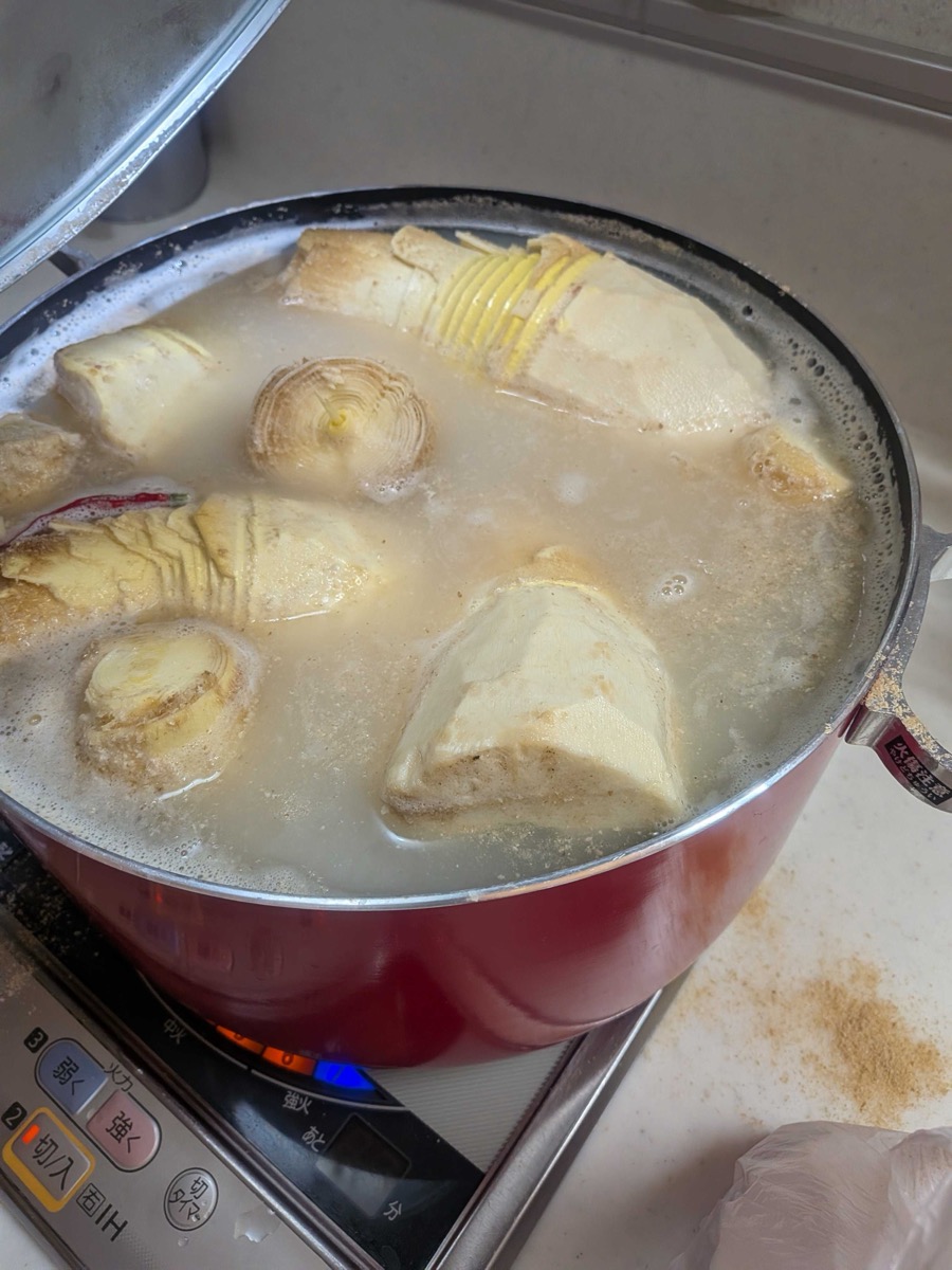 Bamboo shoots boiling in a large red pot with rice bran water
