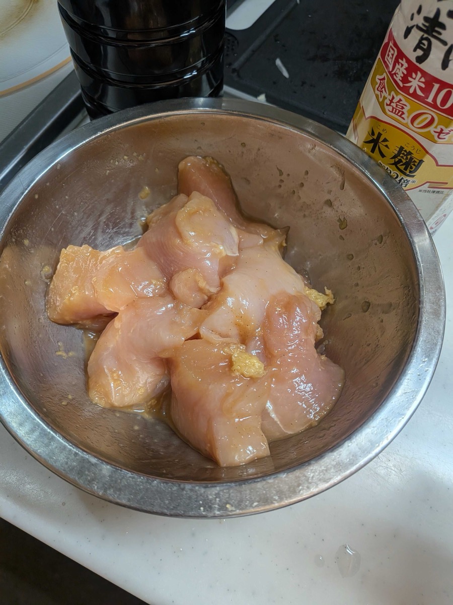 Chicken pieces marinating in soy sauce, sesame oil, ginger and garlic in a metal bowl