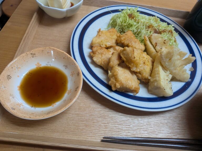 Tori ten on a plate with shredded cabbage and ponzu dipping sauce on the side
