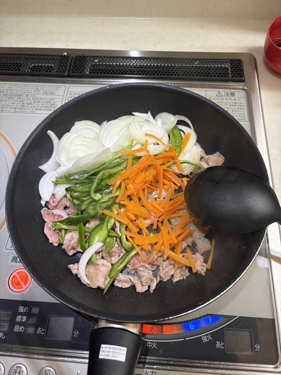 Sliced onion, julienned carrot, and green pepper strips just added to the frying pan with the par-cooked pork, ready to stir-fry together