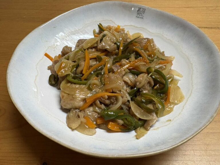 Japanese pork and vegetable sweet-and-sour stir-fry — buta amazu itame — served on a rustic blue-rimmed Portuguese ceramic plate, glossy with sauce and full of julienned carrot, onion, and green pepper
