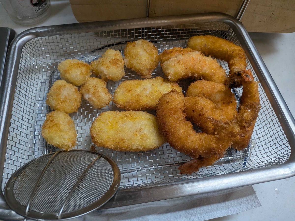 Golden-brown panko-fried ebi fry shrimp draining on a wire rack — the panko is shaggy and deep golden, the tails sticking up