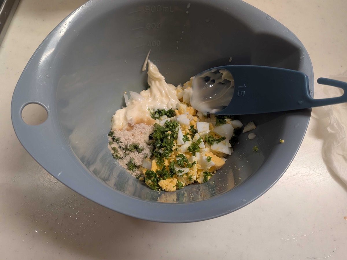 Tartar sauce ingredients in a grey mixing bowl before stirring — minced egg, onion, parsley, Kewpie mayo, and salt