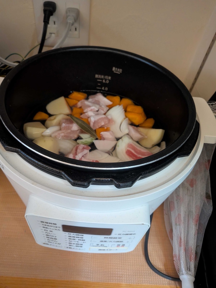Electric pressure cooker with curry ingredients and water loaded inside, ready to start cooking