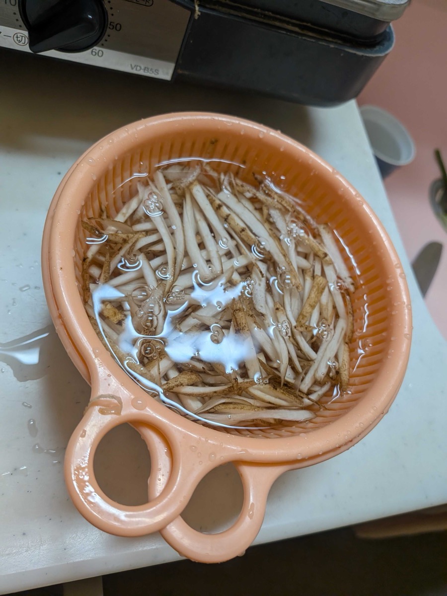 Julienned burdock root soaking in a bowl of cold water to remove bitterness before cooking