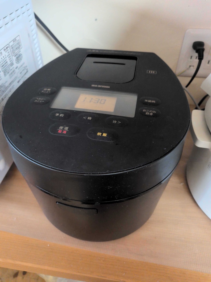 An Iris Ohyama IH induction rice cooker on a wooden counter, showing the digital display — used daily in Japanese home kitchens for perfect rice with zero attention required