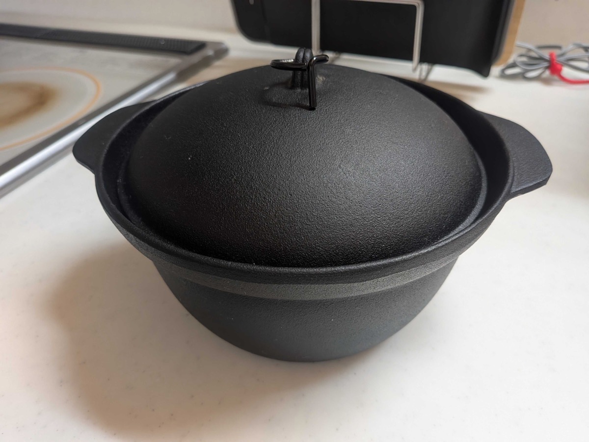 A Japanese nanbu tekki cast iron rice pot with its heavy domed lid in place, sitting on a counter — a traditional ironware from Iwate Prefecture used for stovetop rice cooking