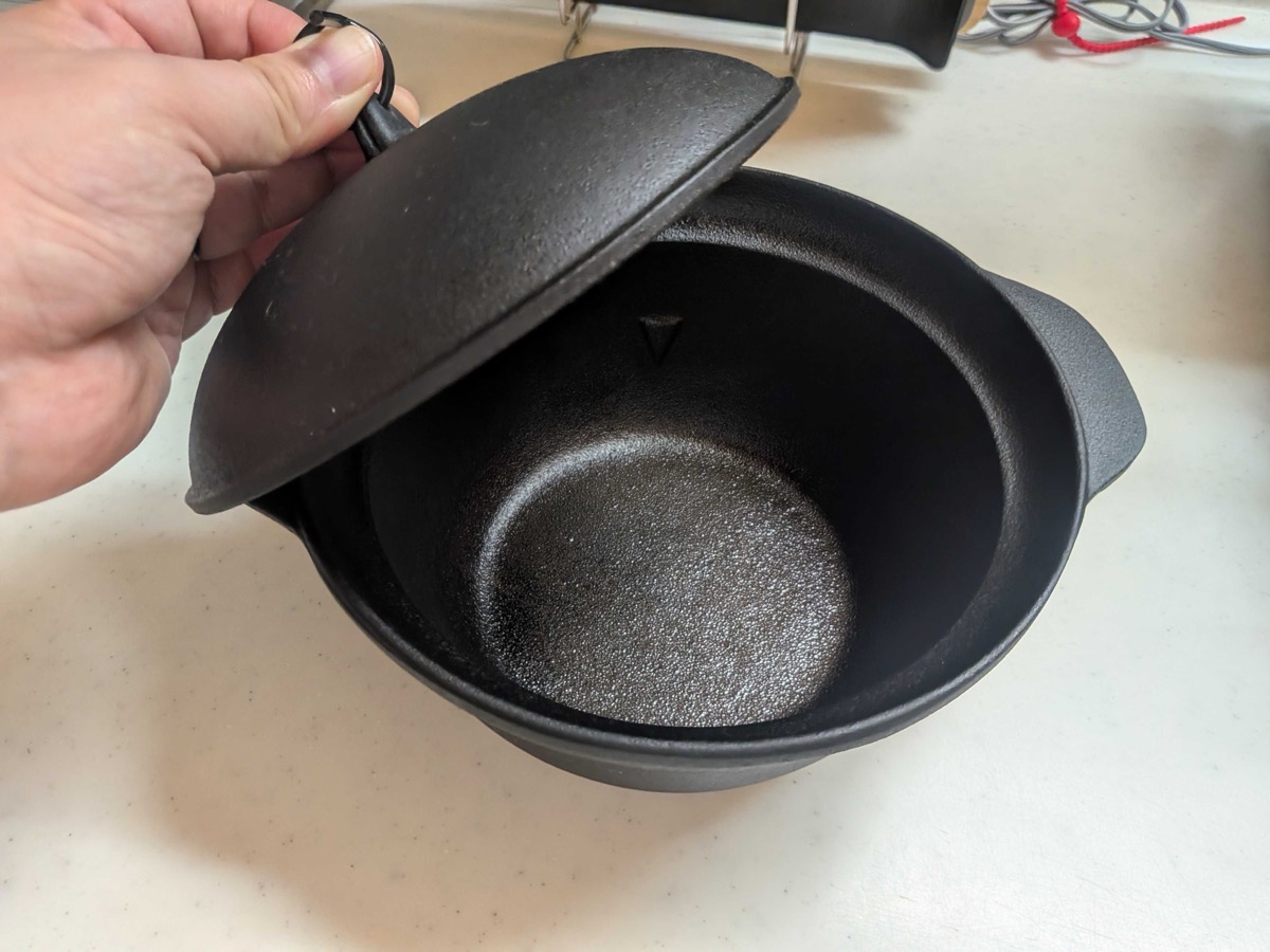 The same nanbu tekki rice pot with the lid lifted — showing the thick-walled cast iron interior, designed for even heat distribution when cooking rice