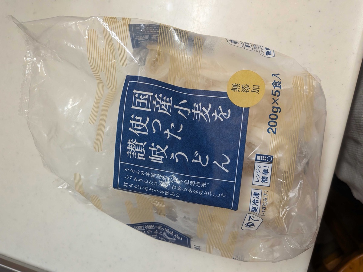 A 5-pack of frozen Sanuki udon noodles (国産小麦・讃岐うどん) in clear plastic packaging, labelled microwaveable