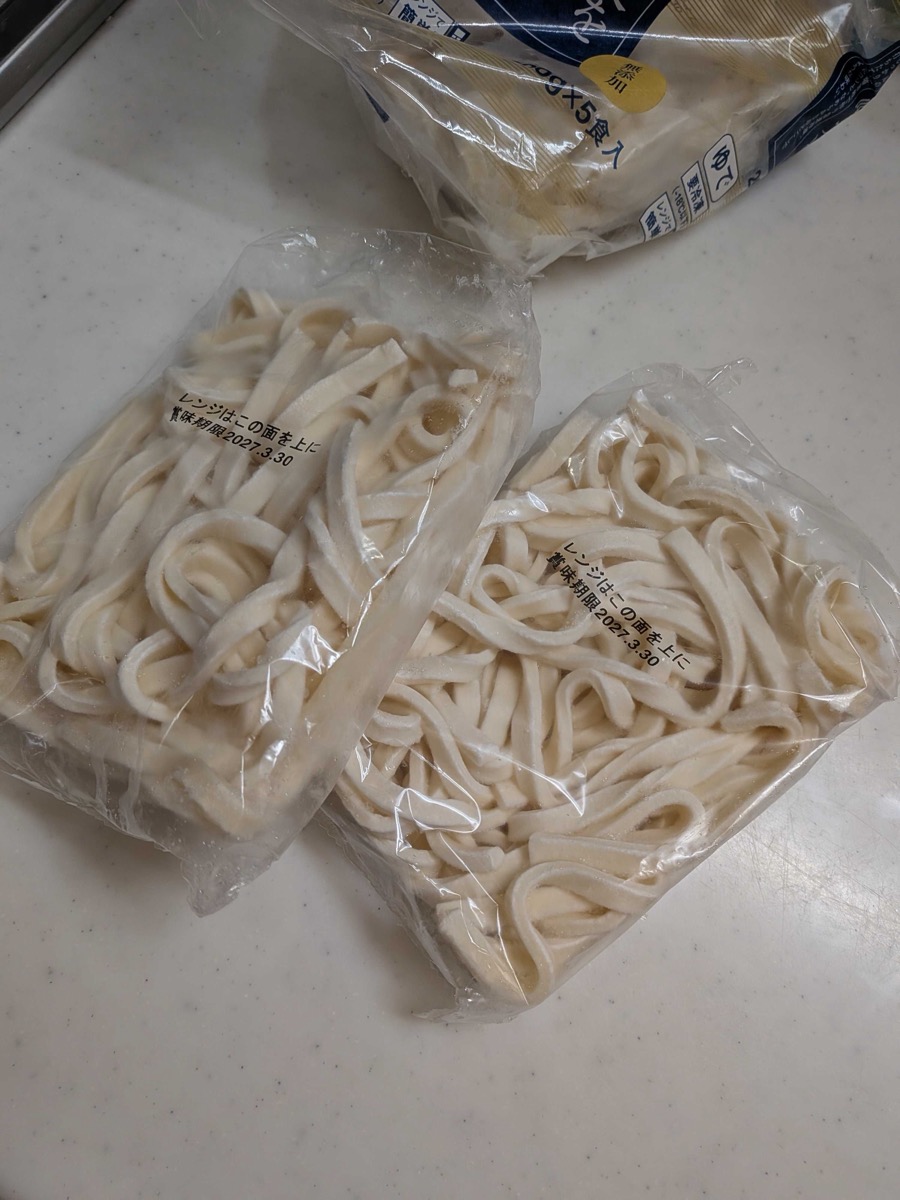 Two individually-packed portions of frozen Sanuki udon noodles on a kitchen counter, ready to be microwaved