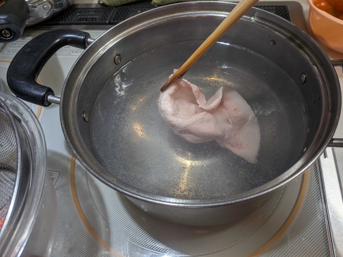 A slice of pork being gently poached in the pot with chopsticks