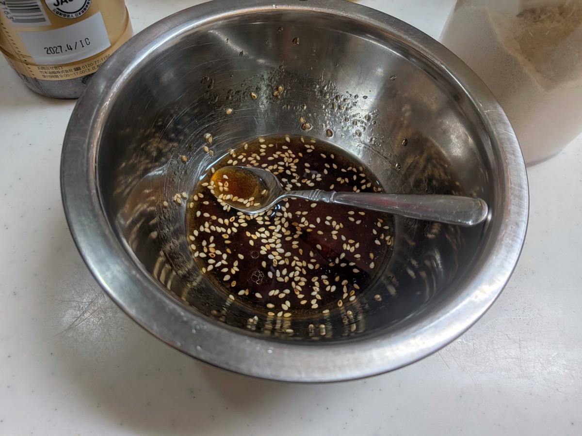The sesame-soy dressing mixed together with sesame seeds in a metal bowl