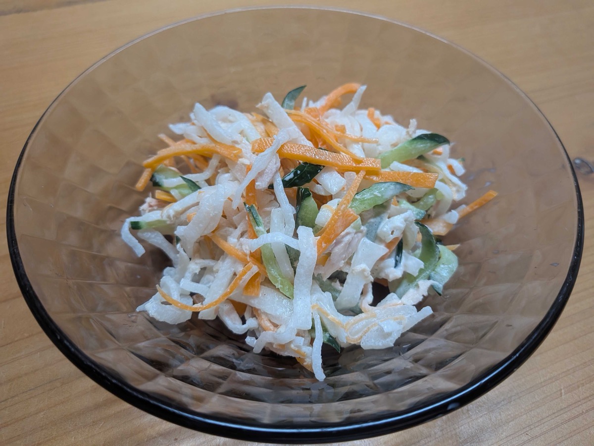 A glass bowl of Japanese daikon salad — shredded daikon, carrot, and cucumber tossed with tuna and mayonnaise