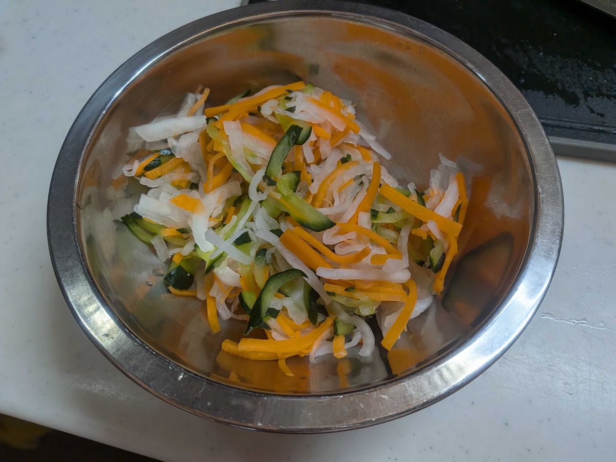 Salted and squeezed shredded vegetables, reduced in volume, in a metal bowl