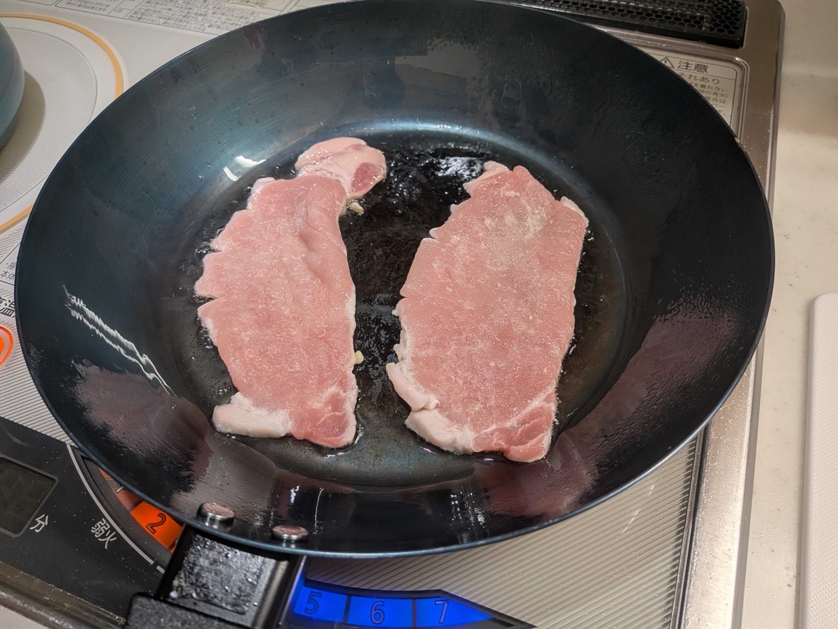 Two thin pork loin steaks frying in a pan