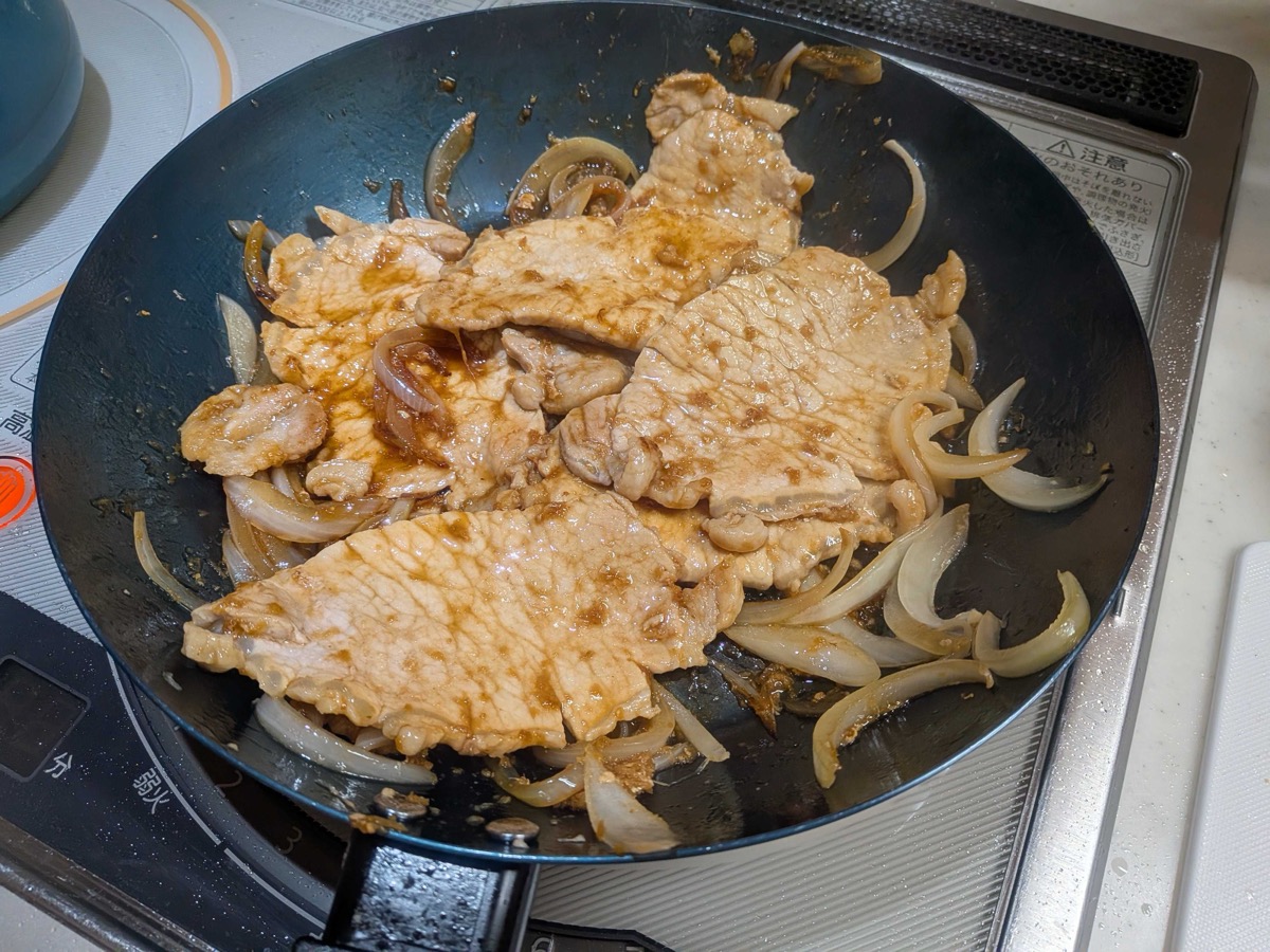 Pork and onion simmering in the glossy ginger sauce in the pan