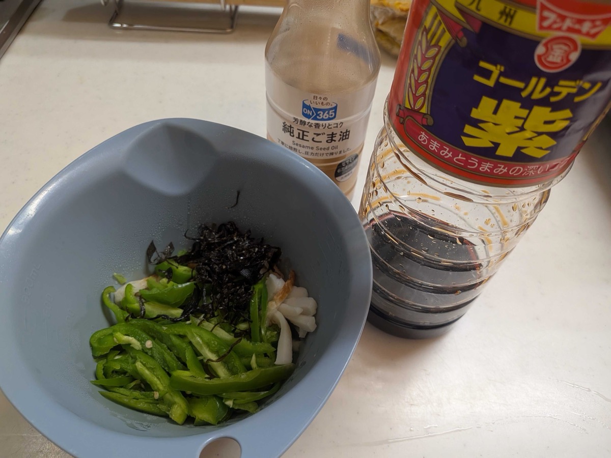Shio kombu added to the drained green pepper and chikuwa, with sesame oil and soy sauce beside the bowl