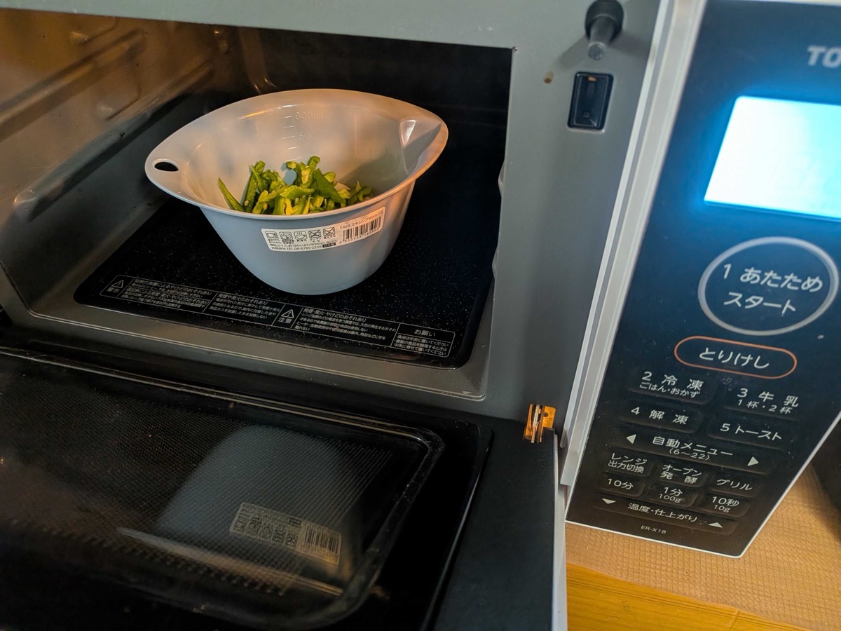A bowl of sliced green pepper in the microwave, ready to soften