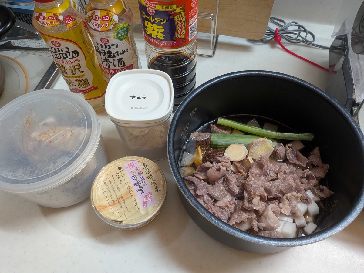 An electric pressure cooker pot filled with beef sinew, cubed daikon, konnyaku, sliced ginger, and a whole scallion green — with bottles of mirin, sake, soy sauce, sugar, and white miso arranged in the background, ready to cook Japanese gyusuji nikomi