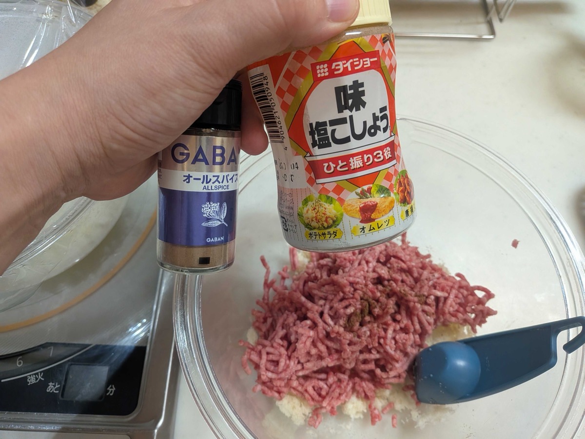 Ground meat added to the panko and onion with salt, pepper, and allspice being seasoned in