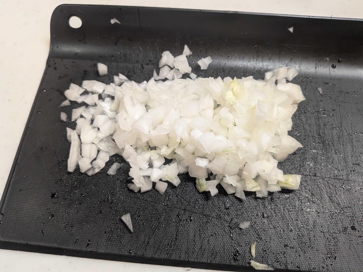 Finely chopped onion on a black cutting board for Japanese hamburg steak