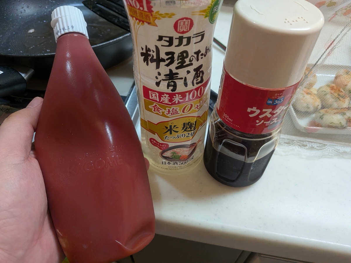 The sauce ingredients — Kagome ketchup, Takara cooking sake, and Worcestershire sauce — held in front of the stove