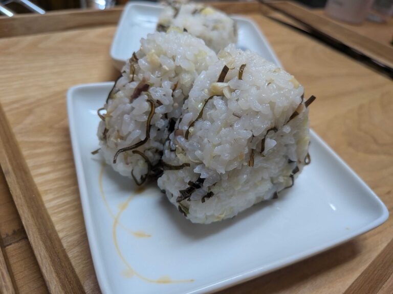 Three triangular myoga and shio kombu onigiri on a white plate
