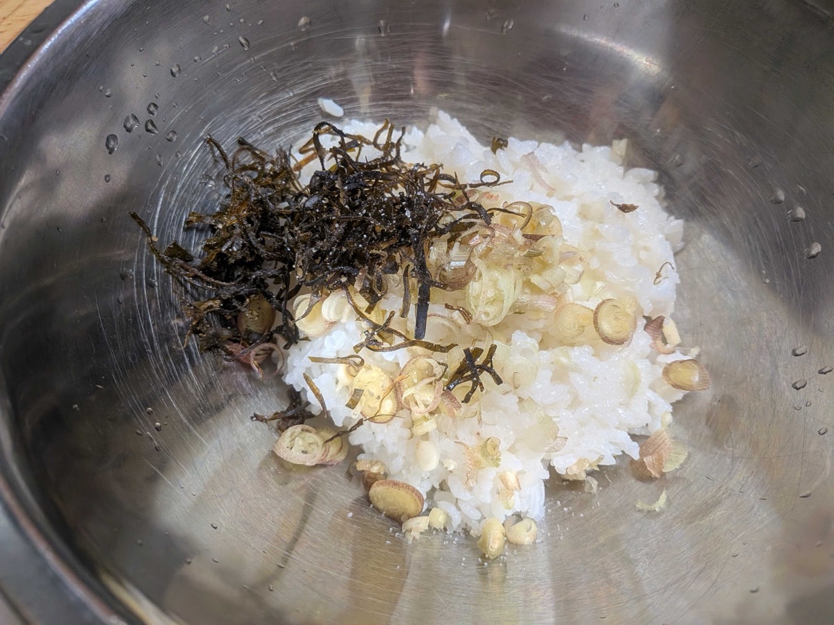 Warm rice in a bowl topped with shio kombu, sliced myoga, and salt before mixing