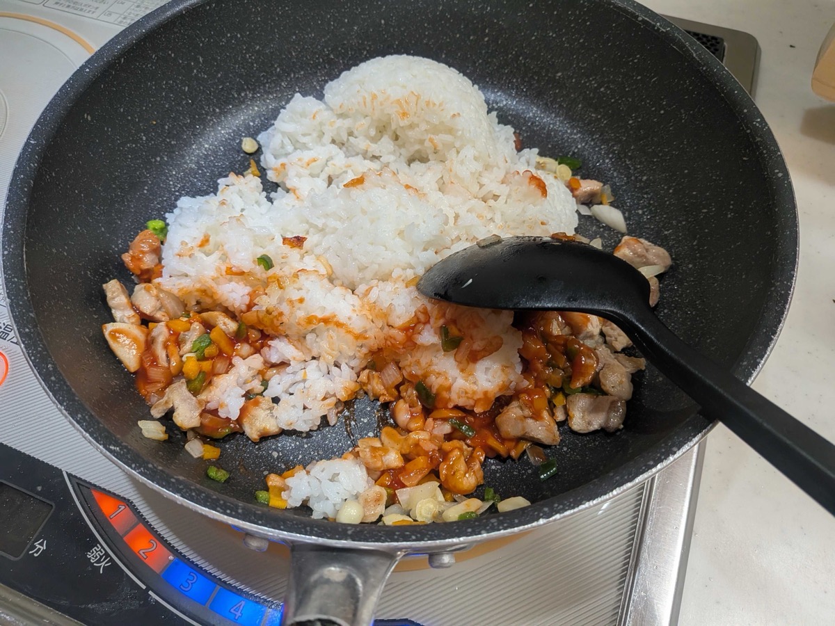 Cooked white rice added to the ketchup chicken and vegetables in the pan