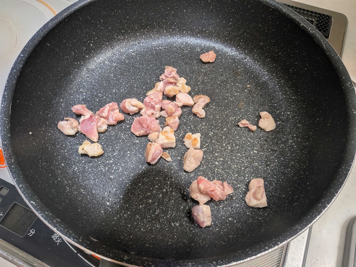 Small pieces of chicken thigh browning in a frying pan