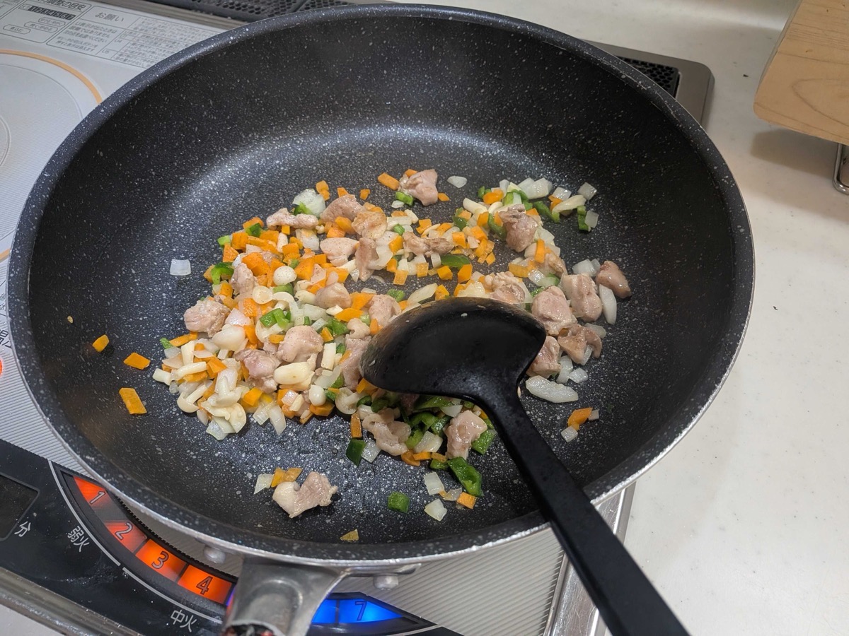 Chicken stir-fried with chopped onion, carrot, and green pepper in a pan