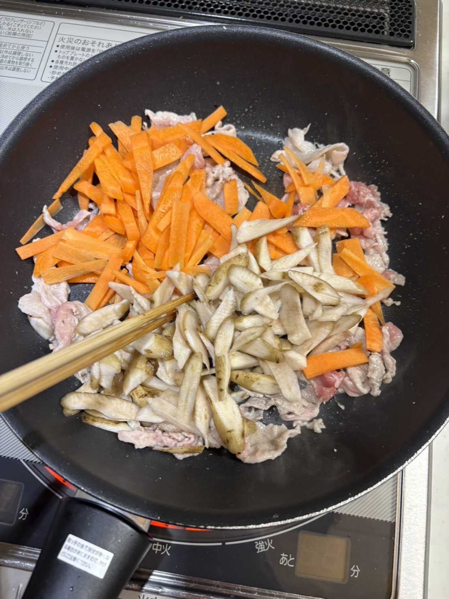 Burdock and carrot matchsticks added to the pork in the pan