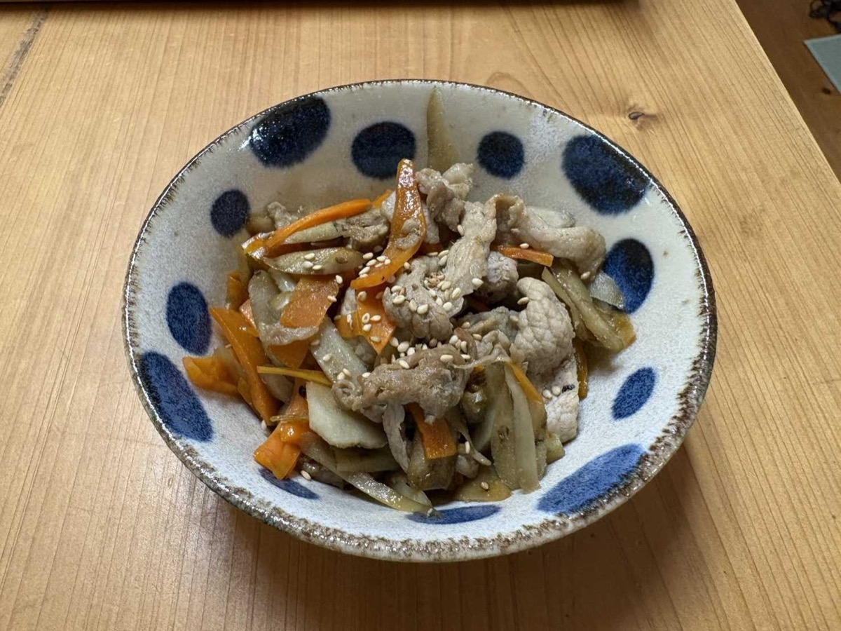 A bowl of pork belly kinpira — burdock, carrot, and pork in a sweet-savory glaze topped with sesame seeds
