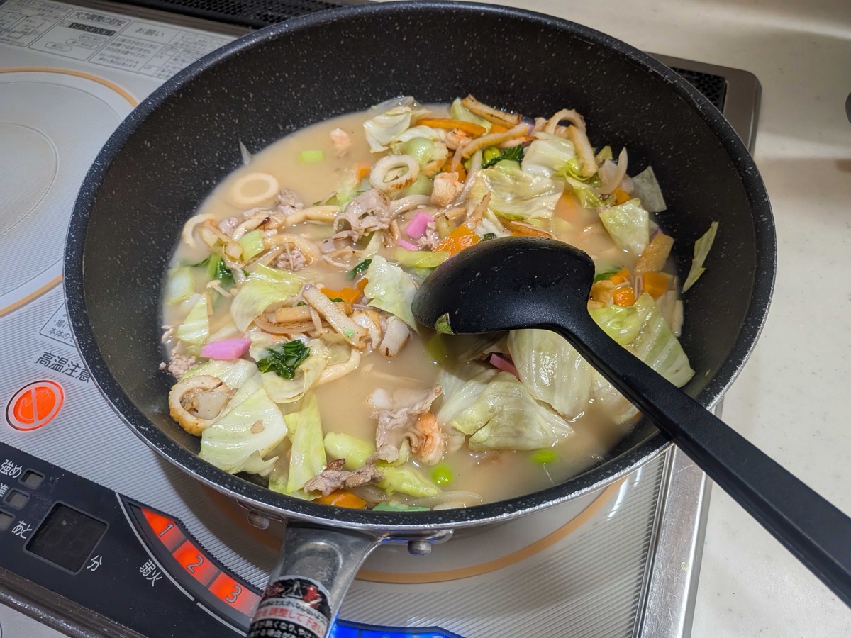 The ankake gravy simmering with the vegetables and seafood in the pan
