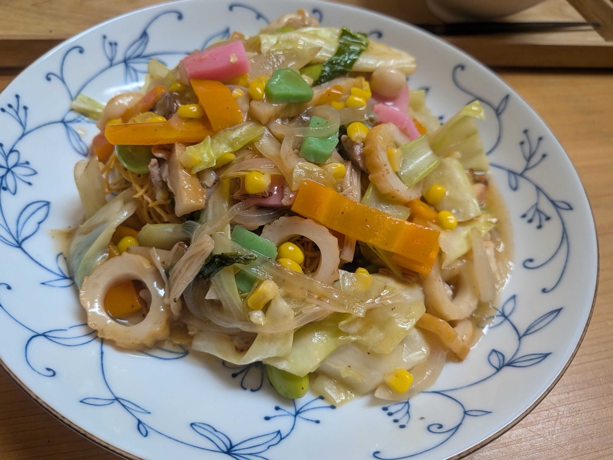 A plate of Nagasaki sara udon — crispy fried noodles topped with a thick ankake gravy of pork, seafood, kamaboko, and vegetables
