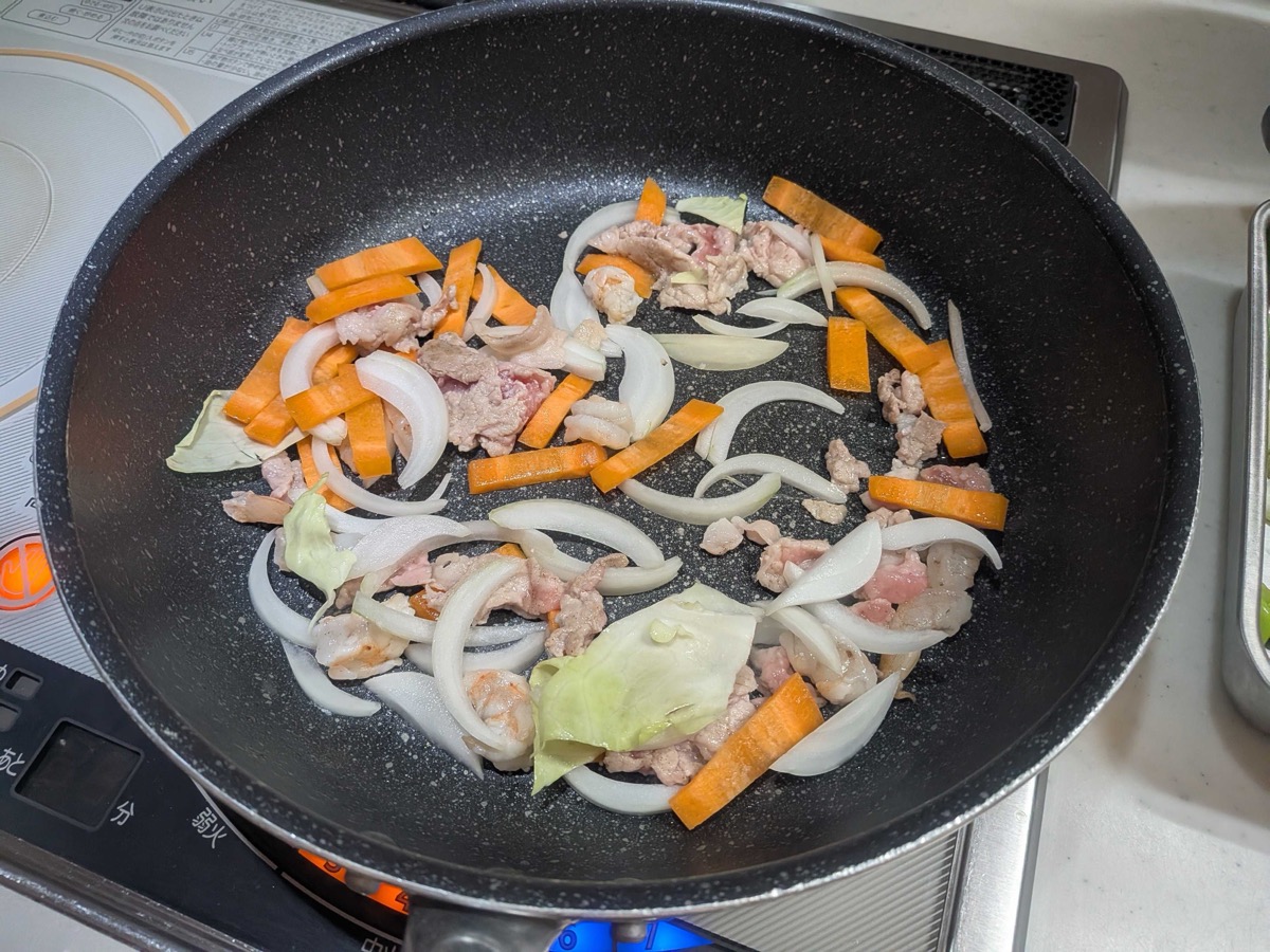 Pork, carrot, and onion stir-frying in a frying pan