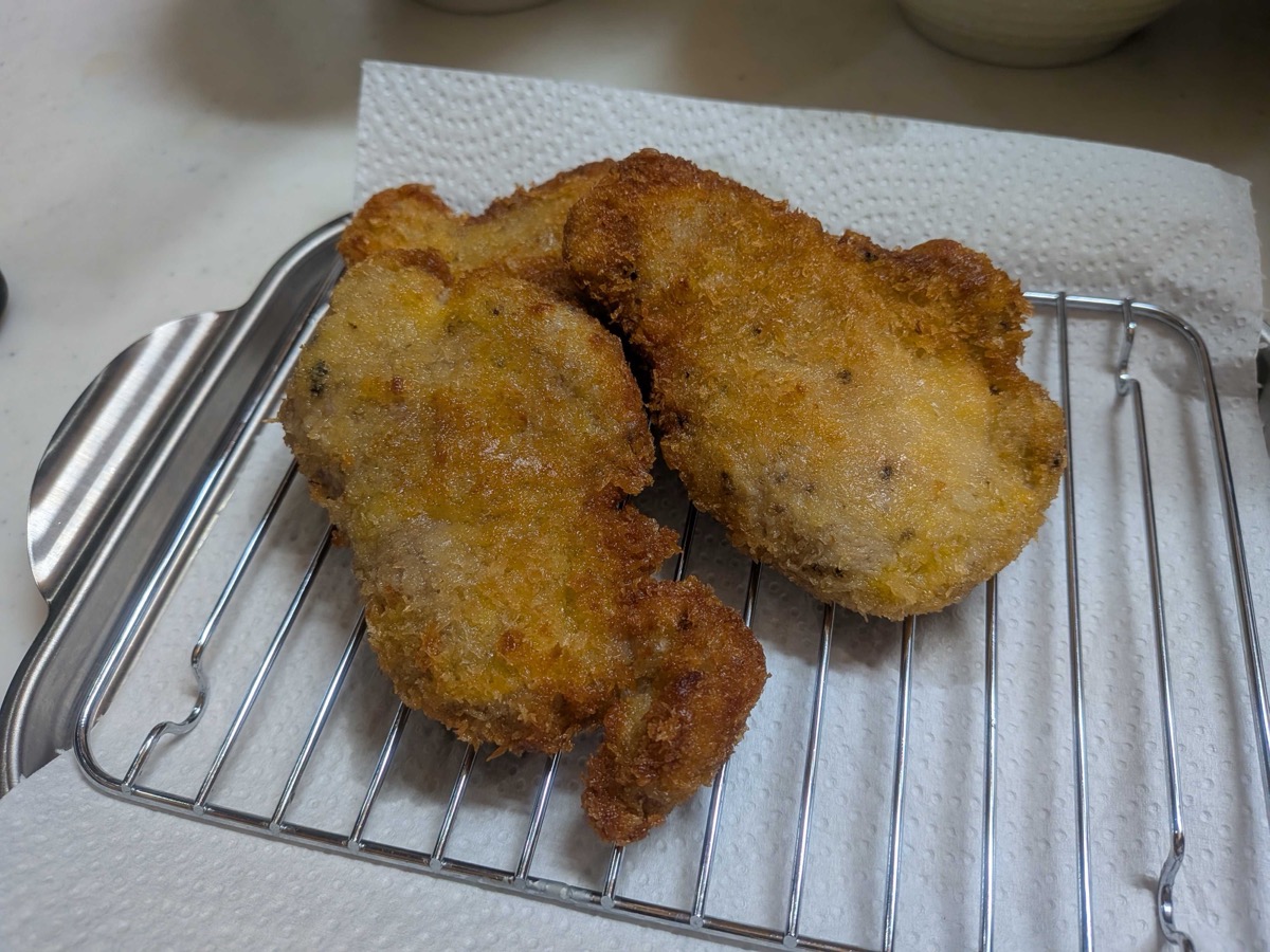 Golden fried pork cutlets draining on a wire rack