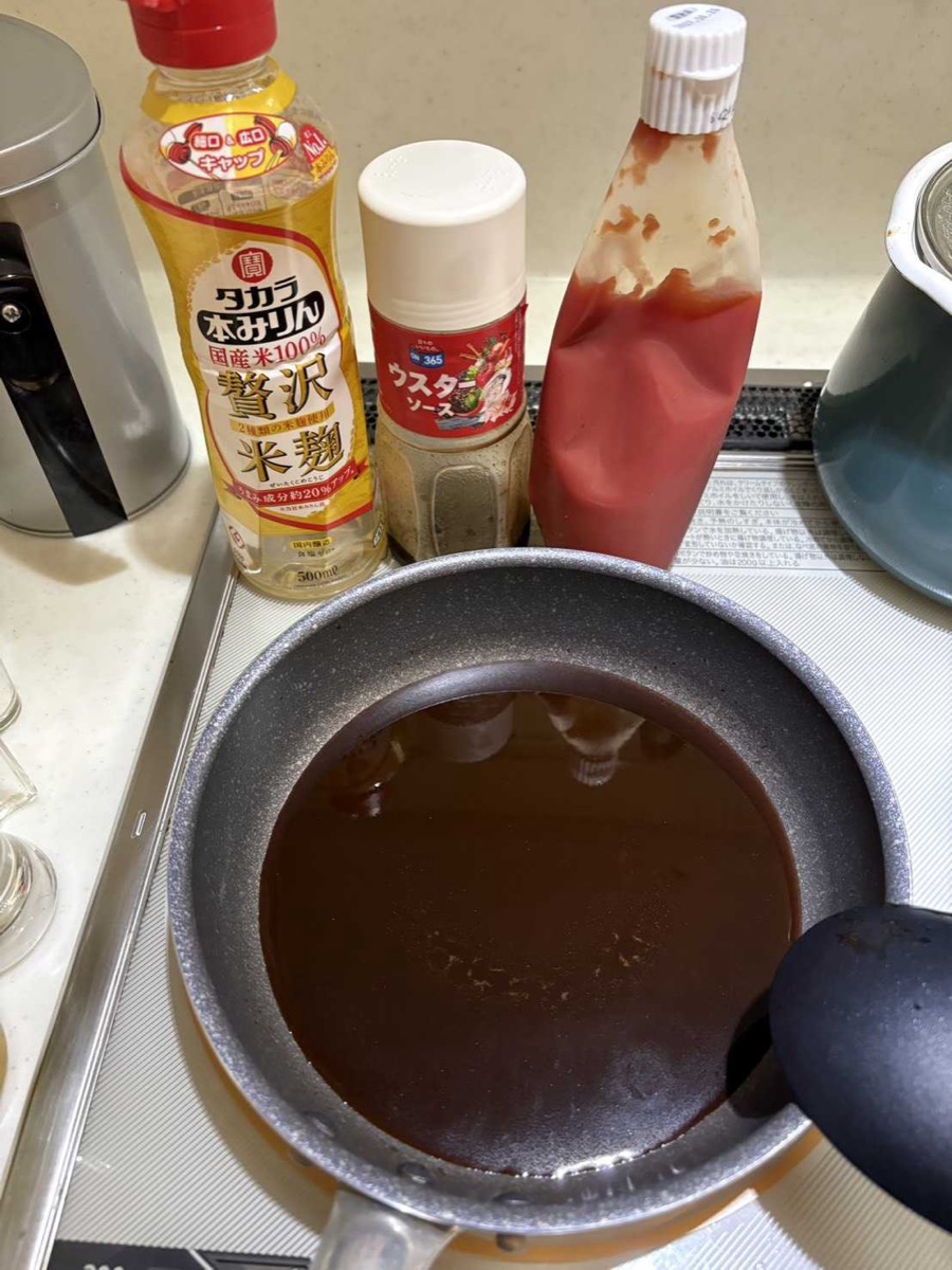 The sauce ingredients — Takara mirin, Worcestershire sauce, and ketchup — behind a saucepan of dark katsudon sauce