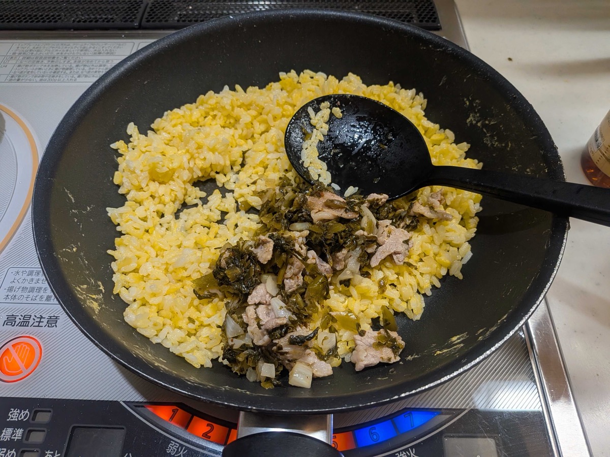 The takana and pork mixture being added back to the golden fried rice in the pan