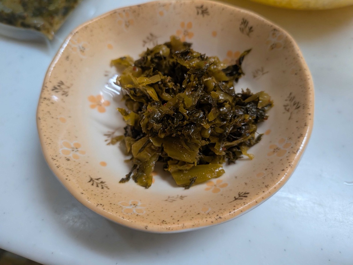 Chopped pickled takana mustard greens in a small floral Japanese dish