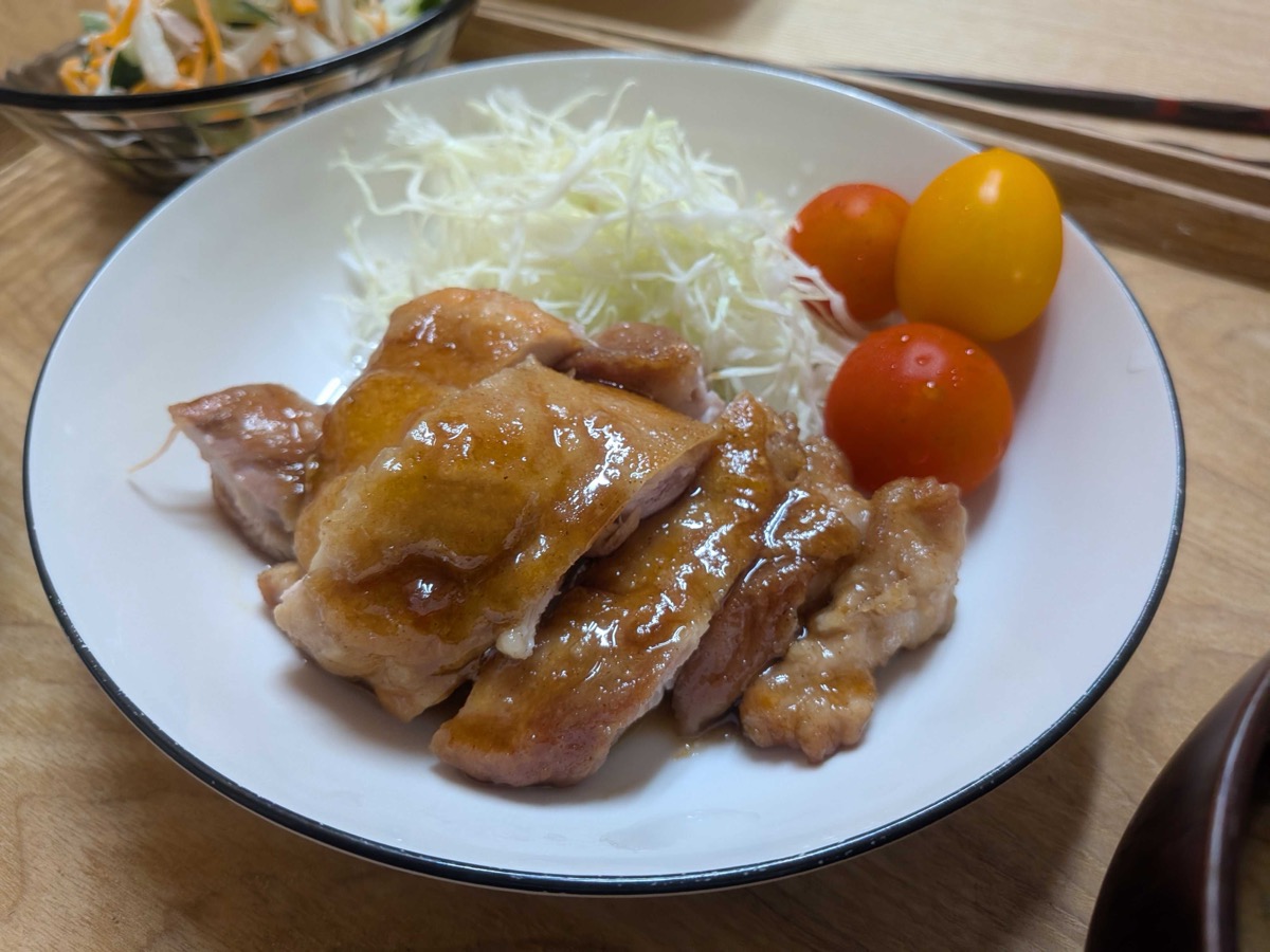Finished Japanese teriyaki chicken sliced on a plate with shredded cabbage, cherry tomatoes, and a side salad