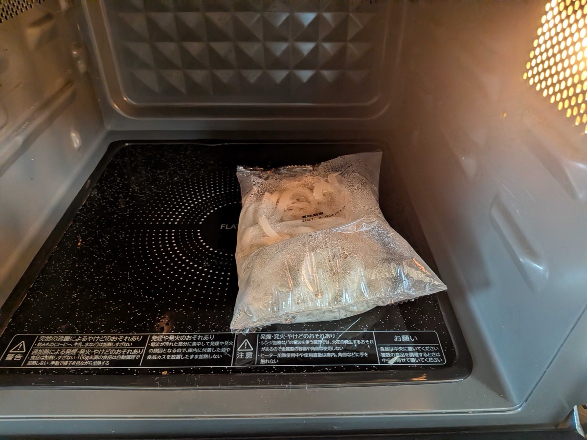A bag of frozen udon noodles heating in the microwave