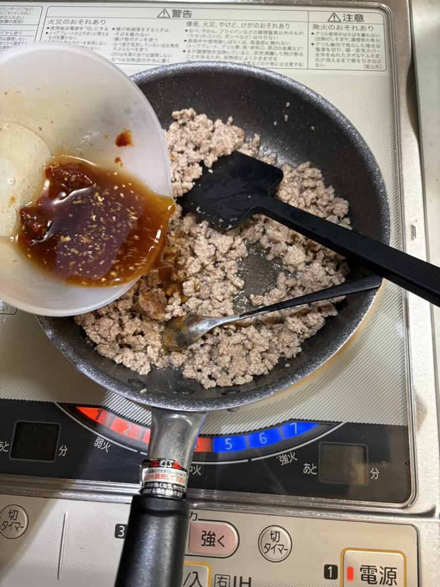 Pouring the sweet-savory gochujang seasoning over browned ground meat in a pan