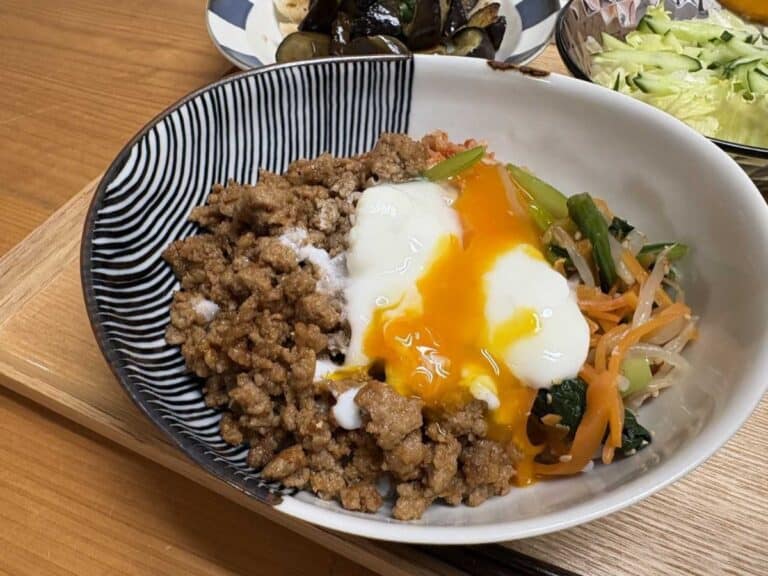 A bowl of bibimbap — rice topped with ground meat, three-color namul, kimchi, and a runny onsen egg